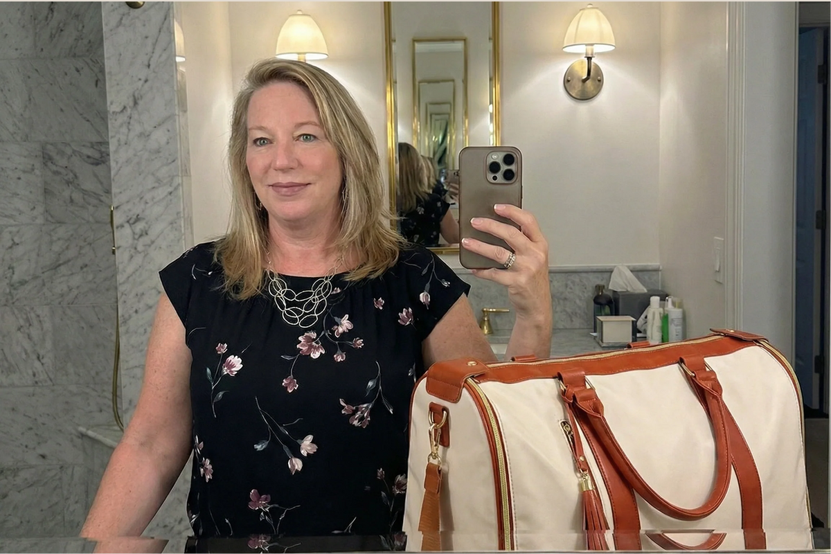 Katherine takes a mirror selfie in a hotel bathroom with her cream and tan Vohxe bag