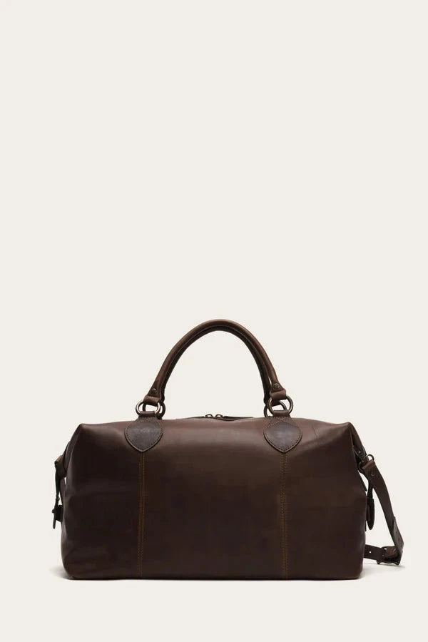 Dark brown leather duffle bag with handles and shoulder strap against a light background.