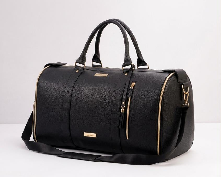 The charcoal black Vohxe Travel Bag 2.0, a clean studio product shot with tan leather trim and gold hardware