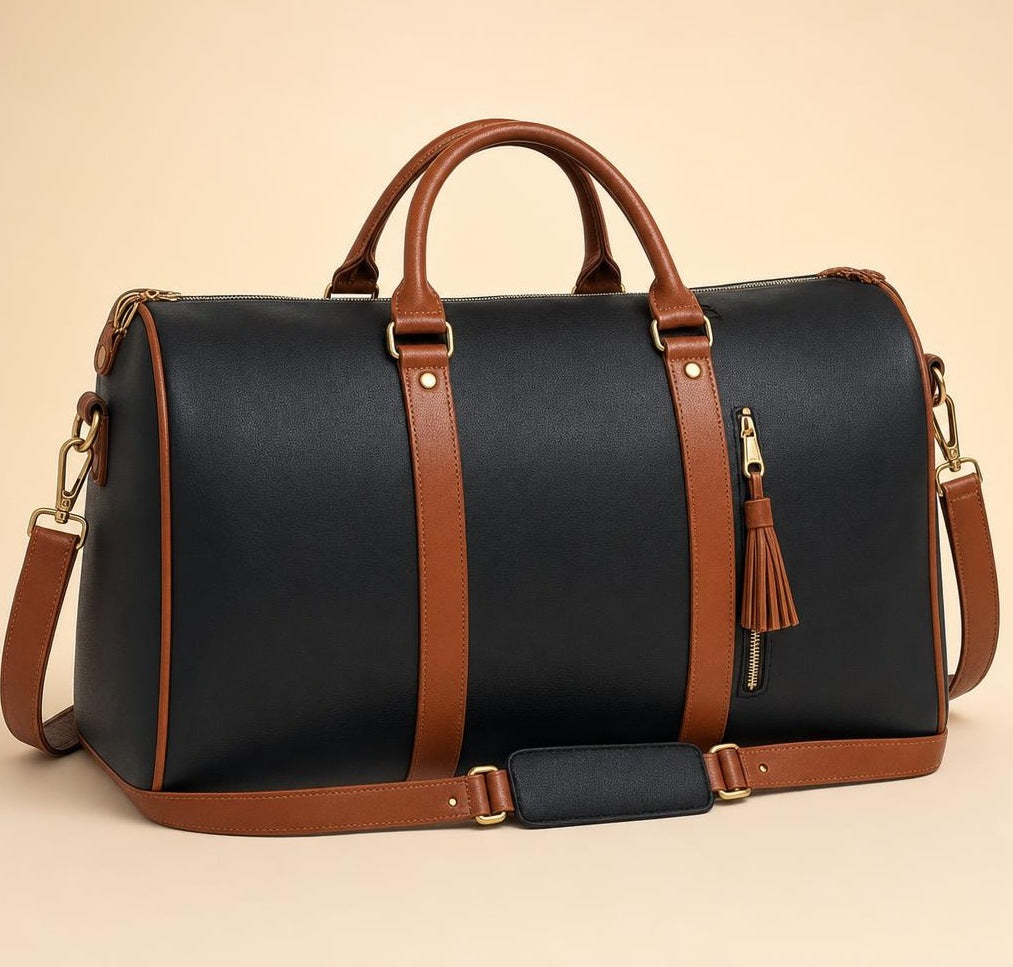 The charcoal black Vohxe Travel Bag 2.0 standing upright, soft vegan leather with gold non-slip zippers and a detachable strap